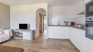 Una cocina moderna con armarios blancos, encimera de madera y horno empotrado.