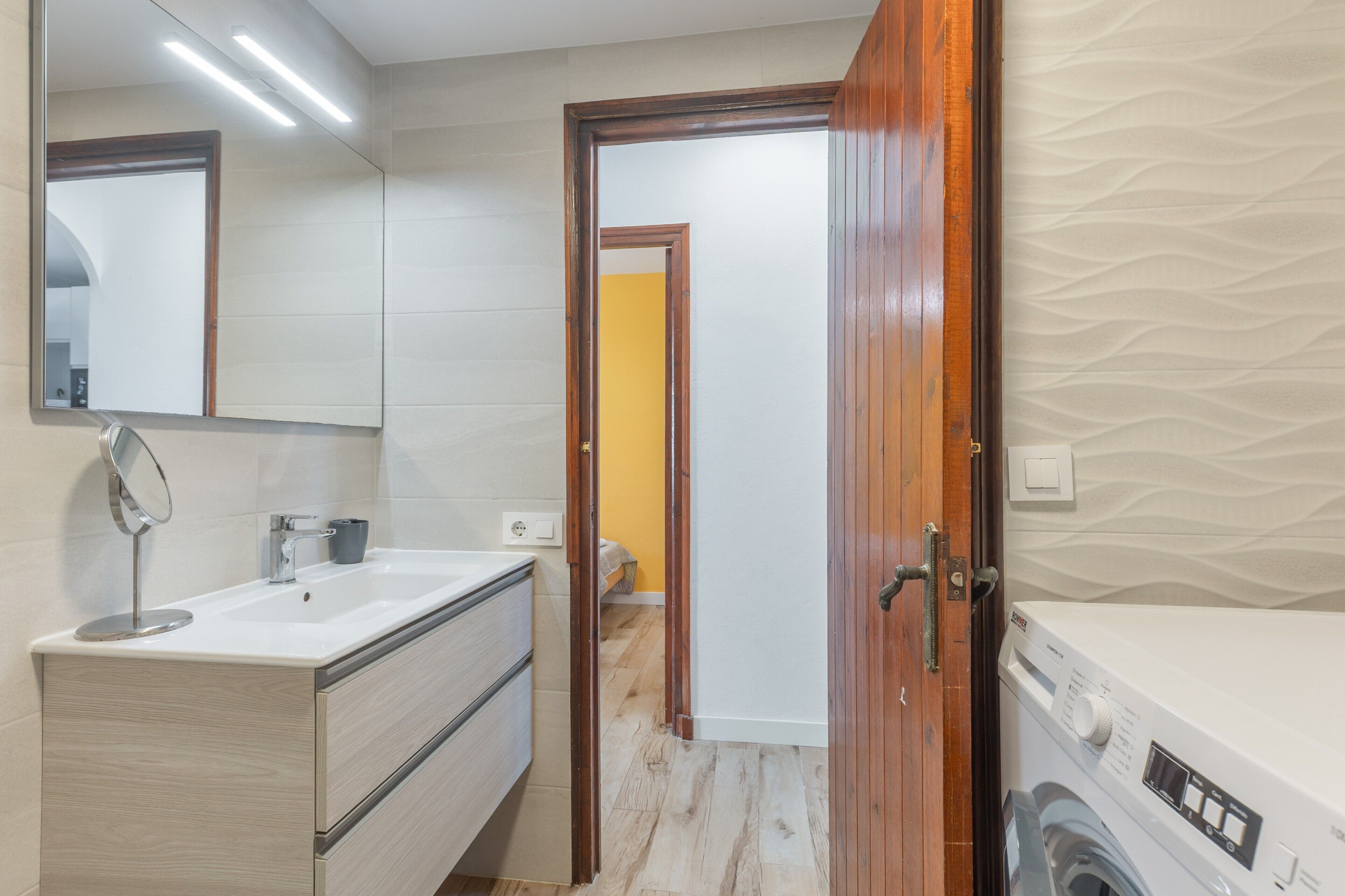 Een badkamer met een wastafel, spiegel en wasmachine.