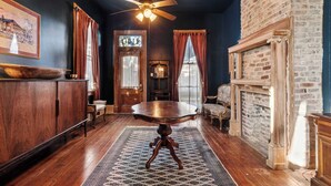 A dining area with a wooden table, a ceiling fan, and a brick wall.