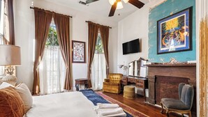 A hotel room with a large bed, a desk, a chair, a TV, and a painting on the wall.