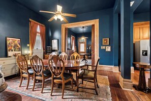 A dining room with a wooden table and chairs, a ceiling fan, and a patterned rug. - Historic Villa, Steps from French Quarter (New Orleans)