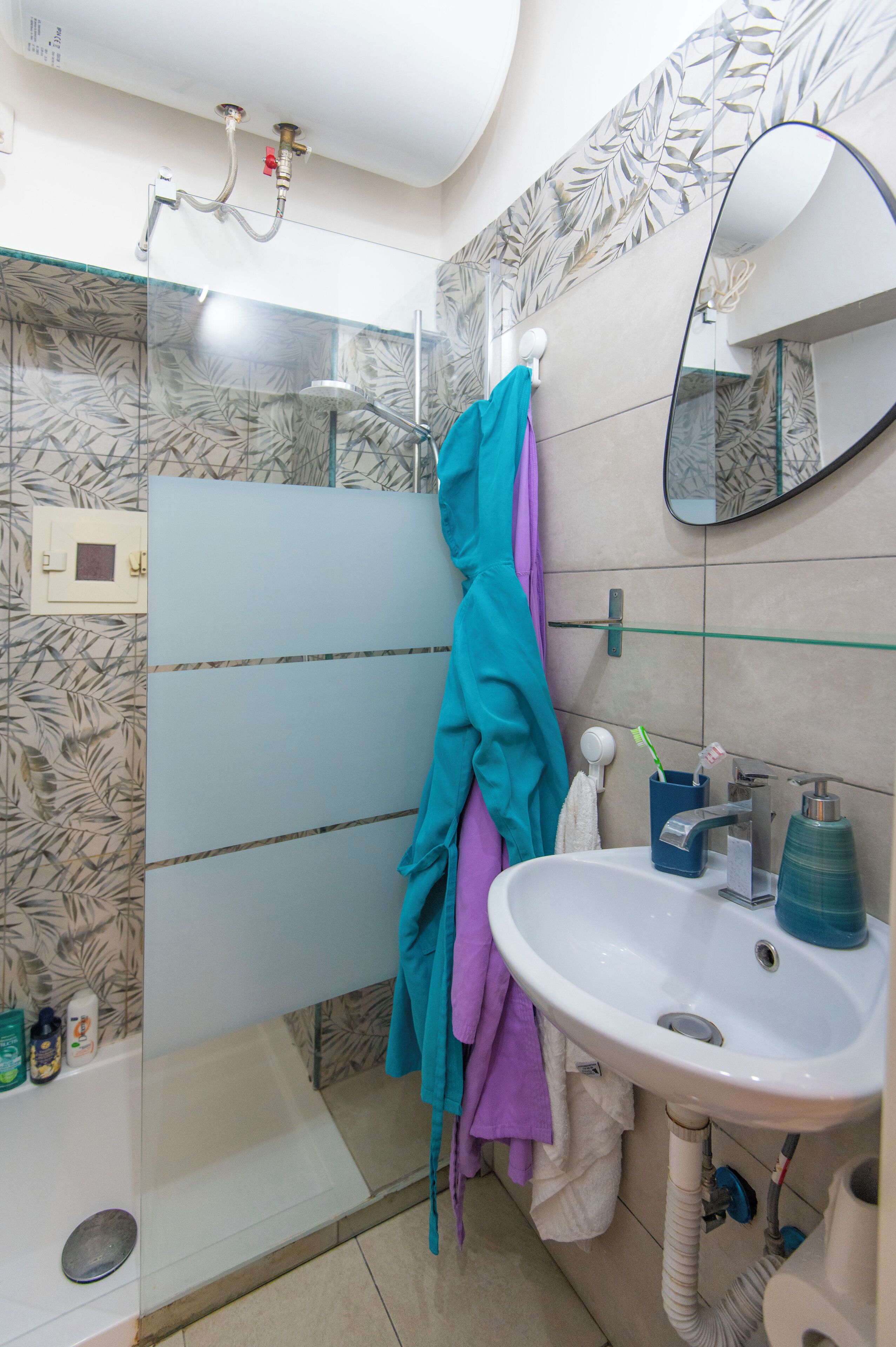 A bathroom with a shower, a sink, and a mirror.