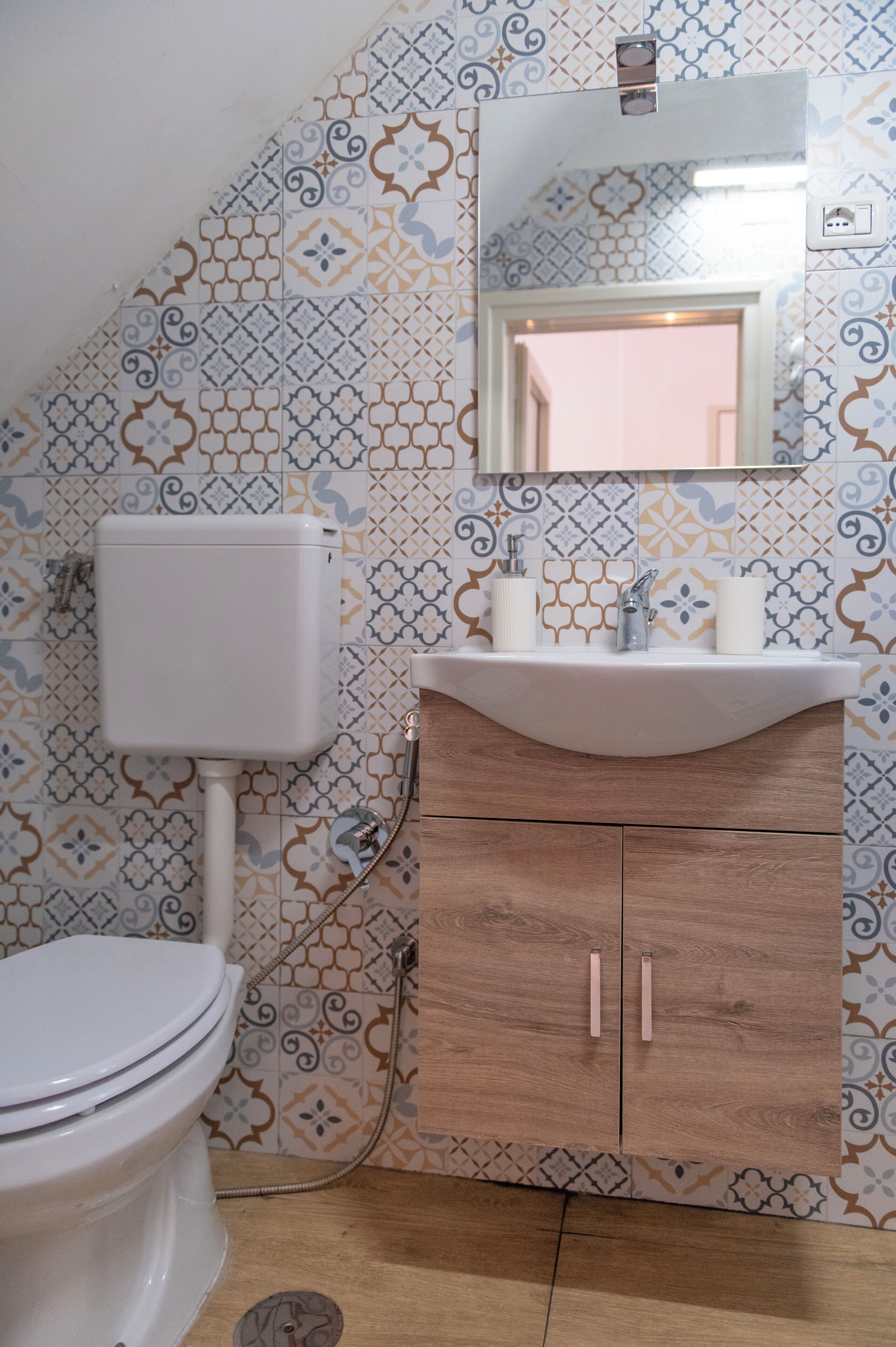 A bathroom with a toilet, sink, and wooden cabinet.