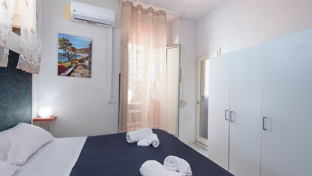 Une chambre d’hôtel avec un lit, une table de chevet avec une lampe, une armoire et un tableau au mur.