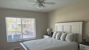 Ein Schlafzimmer mit Bett, Nachttisch, Lampe und Fenster mit Jalousien.