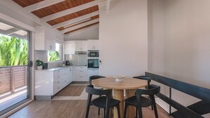 Een moderne keuken met witte kasten, een houten eettafel en zwarte stoelen.