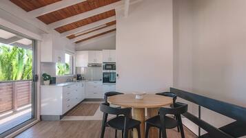 Una cocina moderna con gabinetes blancos, una mesa de comedor de madera y sillas negras.