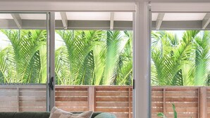 Een moderne woonkamer met een groene bank, een geruit kussen, een potplant en een betegelde salontafel.