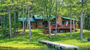 A cabin with a dock extending into a lake, surrounded by trees. - Bua Northwoods Chalet on the Peninsula (Crystal Falls)