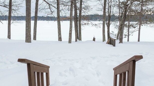 A snow-covered path leading to a wooden bench with a view of trees and a body of water in the background. - Bayview Cottage 3BR Fireplace Lakefront (Saint Germain)