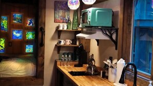 Une cuisine chaleureuse avec des poutres en bois, un four à micro-ondes, un évier et une fenêtre donnant sur un paysage agréable.