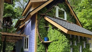 Une maison avec un toit en pente, un porche avec des marches et une fenêtre.