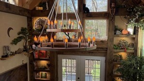 L’intérieur d’un chalet rustique, avec un plafond en bois, un lustre central, une cheminée et un coin salon confortable.