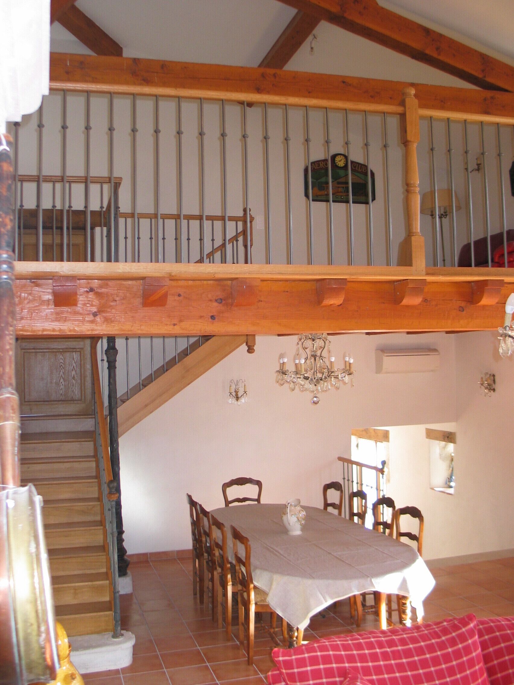 Un espace repas comprenant une table et des chaises, un lustre et un escalier menant à un niveau supérieur.