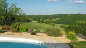 A swimming pool with a view of a golf course and surrounding greenery.