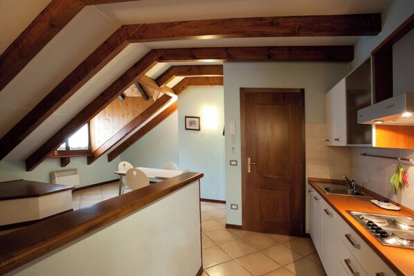 Una cocina con vigas de madera, encimera blanca y piso de baldosas.