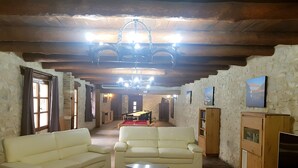 A rustic interior with a sofa, a coffee table, a television, and a billiards table.