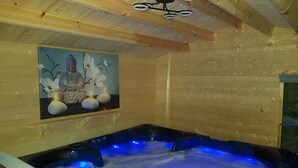 A wooden interior with a hot tub, a painting of a statue, and a ceiling with circular lights.