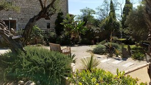 A stone building with a courtyard, surrounded by various plants and trees.