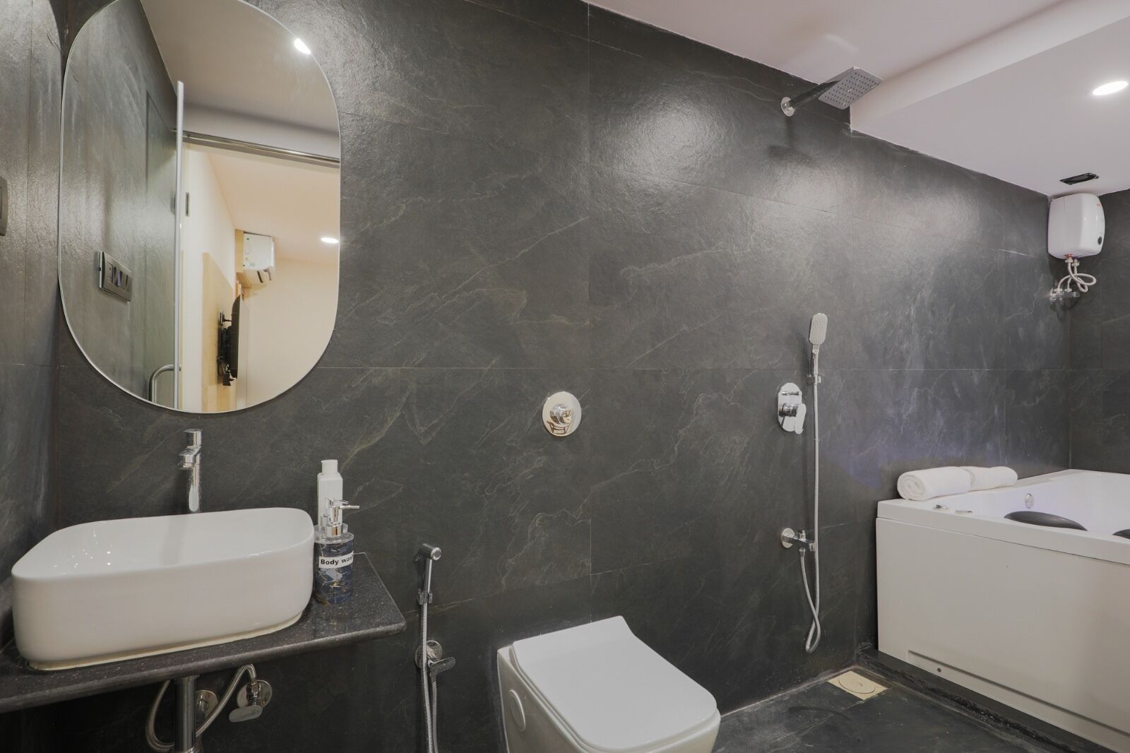 A modern bathroom with a large mirror, a bathtub, a toilet, and a shower.