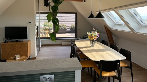 Een moderne keuken met een eethoek, een televisie en een groot raam.
