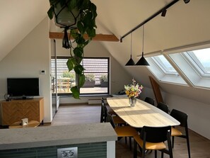Eine moderne Küche mit Essbereich, Fernseher und einem großen Fenster.