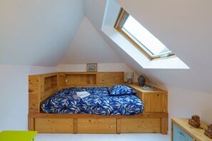 A bedroom with a sloped ceiling and a skylight, wooden furniture, and a bed with a blue floral bedspread. - Ti kouign amann - Proche du Port (Douarnenez)