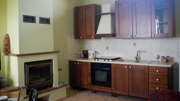 Une cuisine avec des meubles de rangement en bois, une cuisinière, un évier et une fenêtre au-dessus de l’évier.