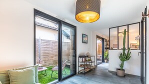 Ein modernes Interieur mit einer Couch, einer Kakteenpflanze und einer Glastür, die zu einem Garten führt.