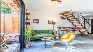 Ein modernes Wohnzimmer mit einem grünen Sofa, einem gelben Sessel und einer Treppe mit Holzbalken.