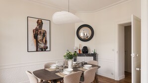 A dining area with a round table, chairs, a vase with flowers, and a framed artwork on the wall. - Ker Marlyne - Proche du Port (Dinard)