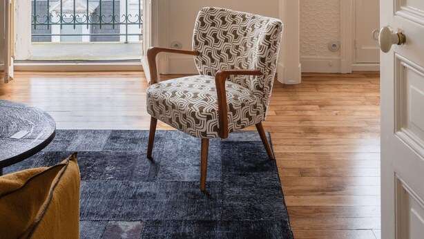 A room with a patterned armchair, a large window with a view of buildings, and a framed artwork on the wall. - Ker Marlyne - Proche du Port (Dinard)