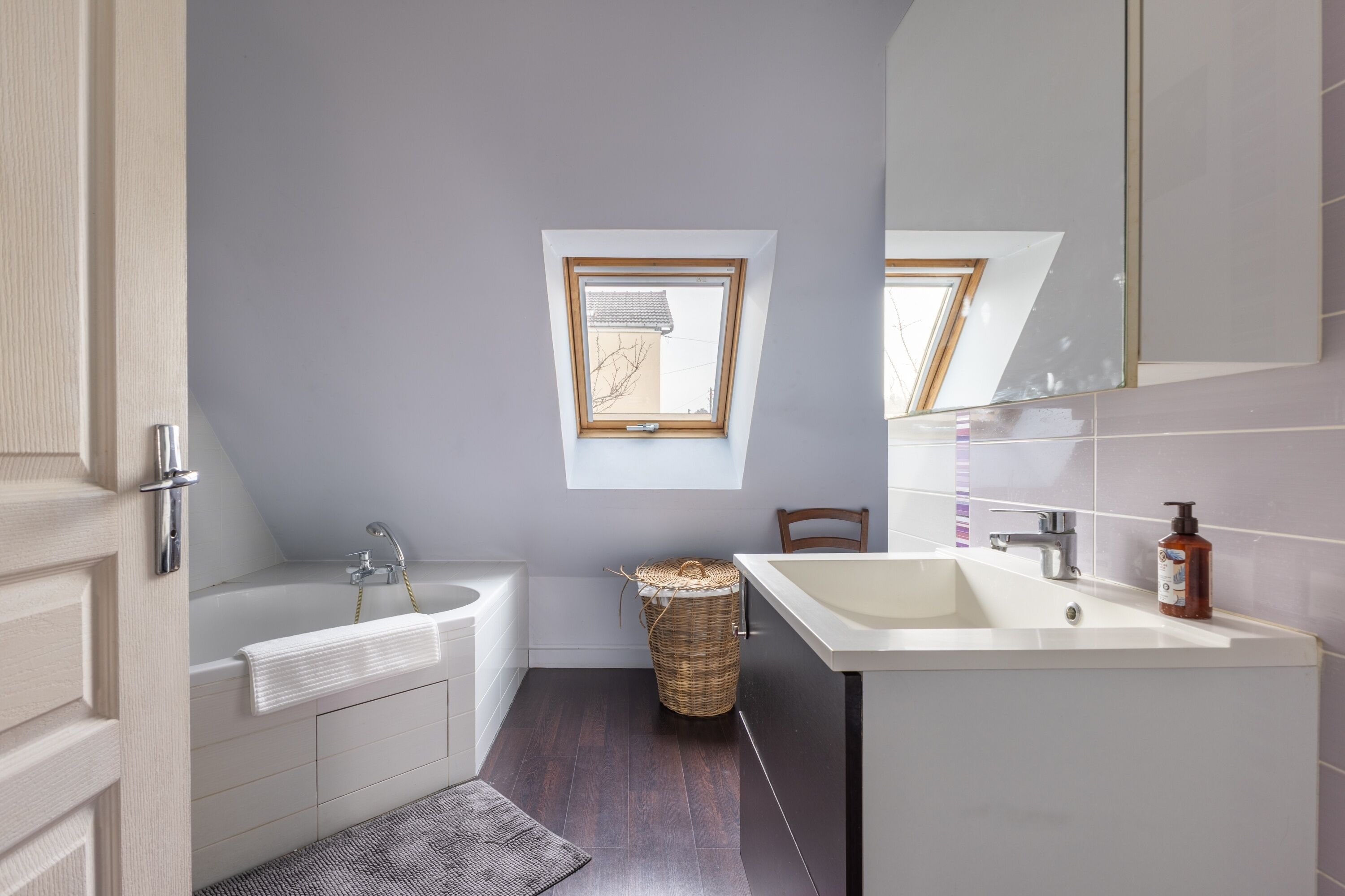 A modern bathroom with a bathtub, a sink, and a window.