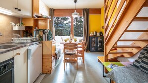 Eine kleine Küche mit Essbereich, einer Holztreppe und Blick ins Freie.