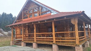 Une cabane en rondins dotée d’un balcon, d’une façade en bois et d’un toit à pente.
