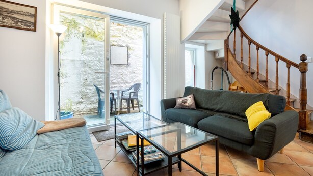 Una sala de estar con un sofá, una mesa de centro de vidrio y una escalera.