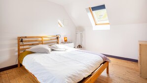 Un dormitorio con cama de madera, una mesita de noche, una lámpara, una ventana con vistas y un armario de madera.