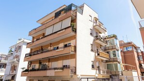 Un immeuble résidentiel à plusieurs étages, doté de balcons, de climatiseurs et d’une entrée de garage bien visible.