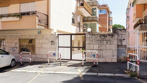 Un parking clos, avec une voiture blanche garée sur le côté gauche.