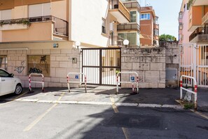 A gated parking area with a white car parked on the left. - Mistrà 18 Vatican House * 10 feet Metro A *parking (Roma)