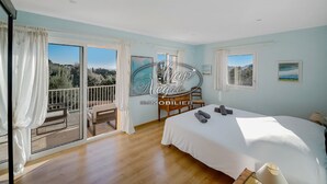 Quarto com uma cama grande, uma escrivaninha e varanda com vista para o exterior.