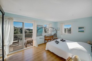 Ein Schlafzimmer mit einem großen Bett, einem Schreibtisch und einem Balkon mit Blick ins Freie.