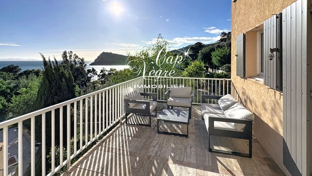 Uma varanda com vista para o mar, um corrimão branco e mobiliário de exterior.