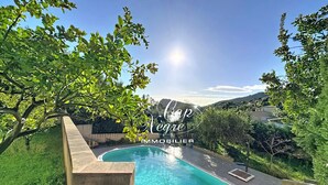Piscina com vista para uma encosta arborizada, sob um céu claro.