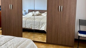 A bedroom with a large wardrobe, a bed, and a chair. - Olinda House in Lazise (Lazise)