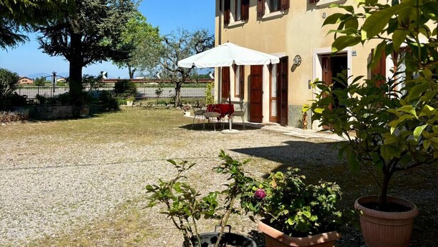 A building with a gravel courtyard, outdoor seating, and potted plants. - Olinda House in Lazise (Lazise)