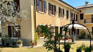 A building with multiple windows and a courtyard with potted plants and a fountain. - Olinda House in Lazise (Lazise)