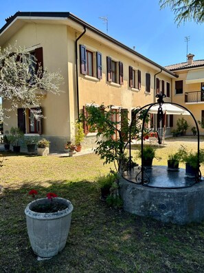 A building with multiple windows and a courtyard with potted plants and a fountain. - Olinda House in Lazise (Lazise)