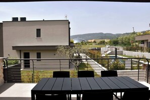 Ein Balkon mit Tisch und Stühlen mit Blick auf ein Wohngebiet, Häuser und einen klaren Himmel.