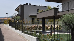 Un edificio residenziale moderno con tetto piatto, balconi e un'area giardino curata.